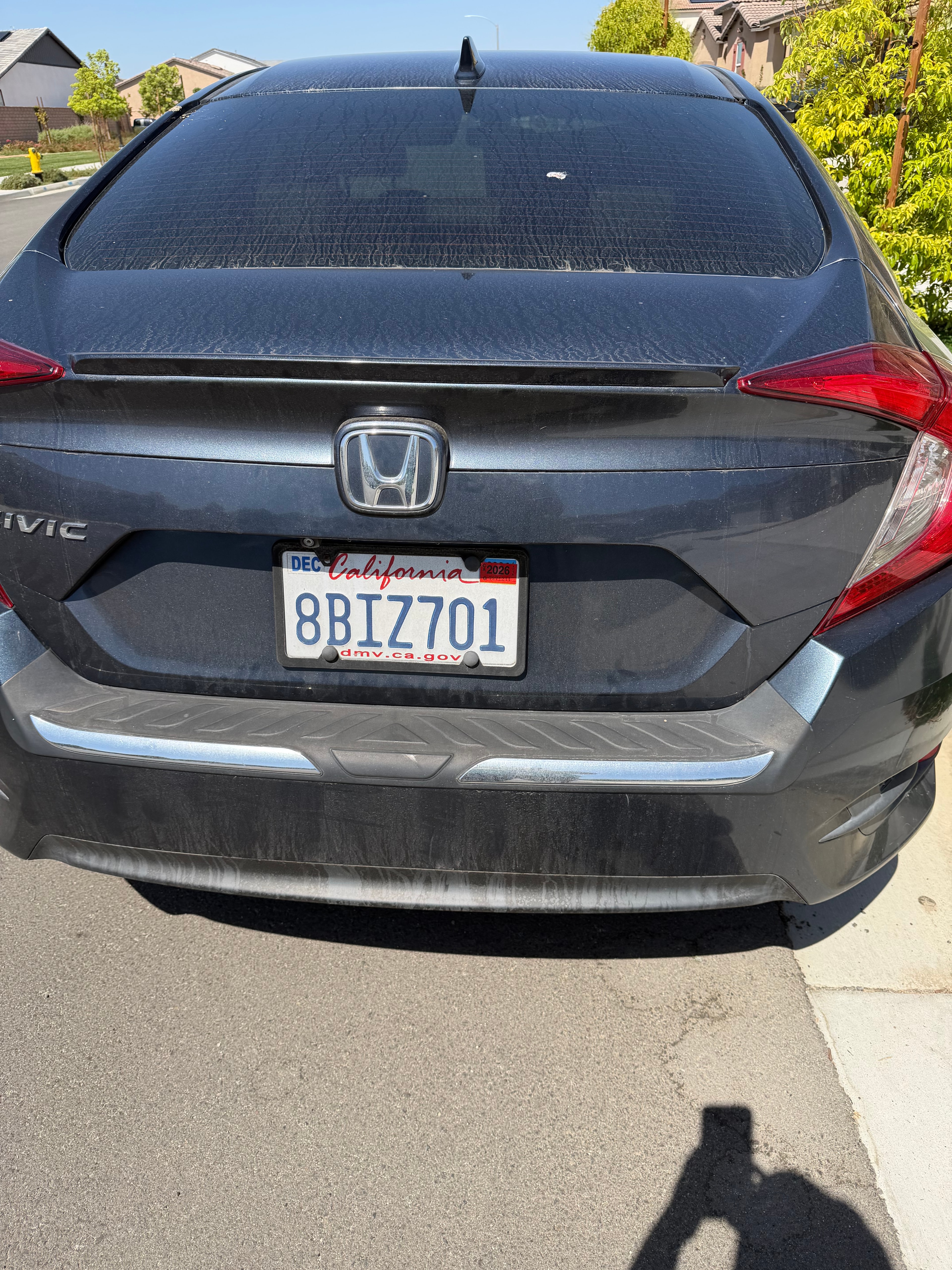 Rear of a blue Honda Civic before detailing, with dirt and streaks on the rear glass, trunk, and bumper.